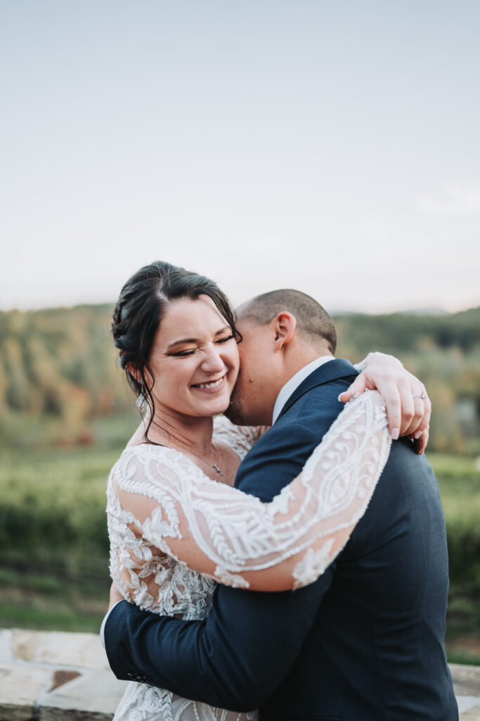 Groom kisses bride's neck at Crane Creek Vineyard