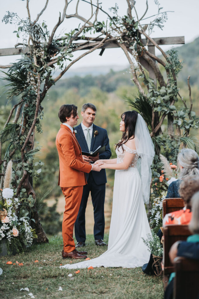 Bride and groom holding hands during ceremony. Wedding at Flat Rock Farms.