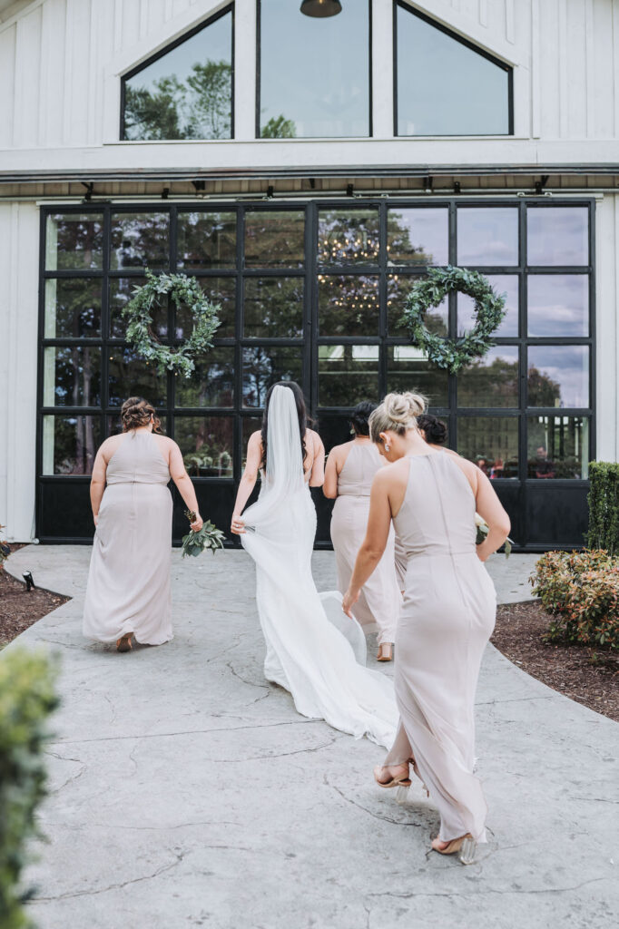 Bride and bridesmaids walking towards venue. Wedding at Meadows at Mossy Creek.