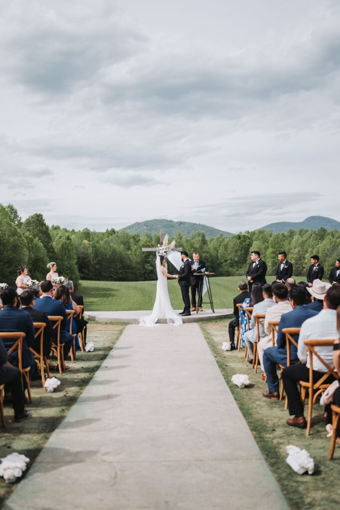 Bride and groom hold hands during ceremony. Wedding at Meadows at Mossy Creek.