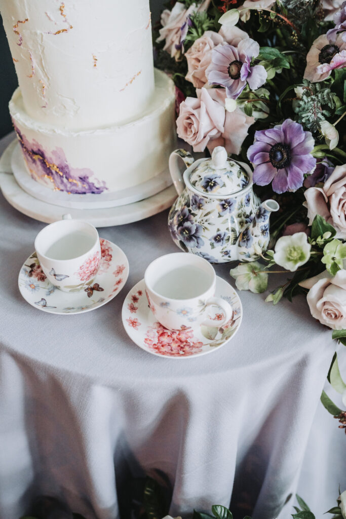 floral teacups near purple bouquet and wedding cake
