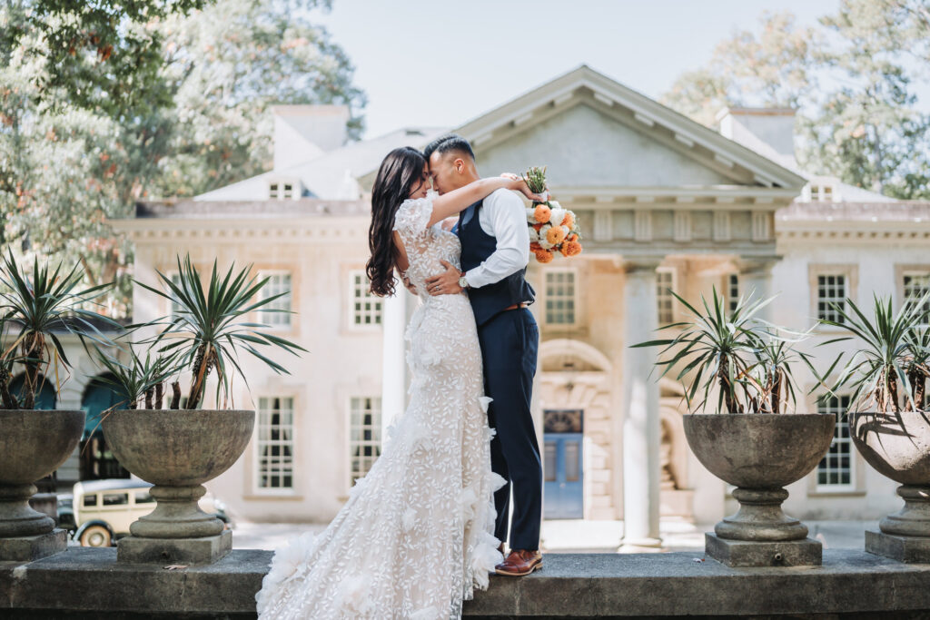 Bride and groom face each other in front of the swan house