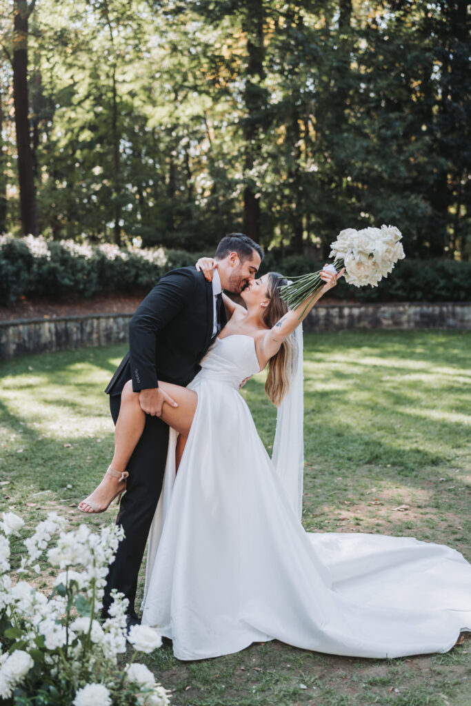 Groom dips bride and she throws her bouquet in the air at the Atlanta History Center Swan House.