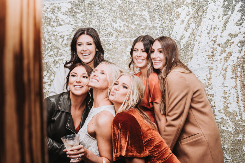 Bride and friends pose in a photobooth at wedding.
