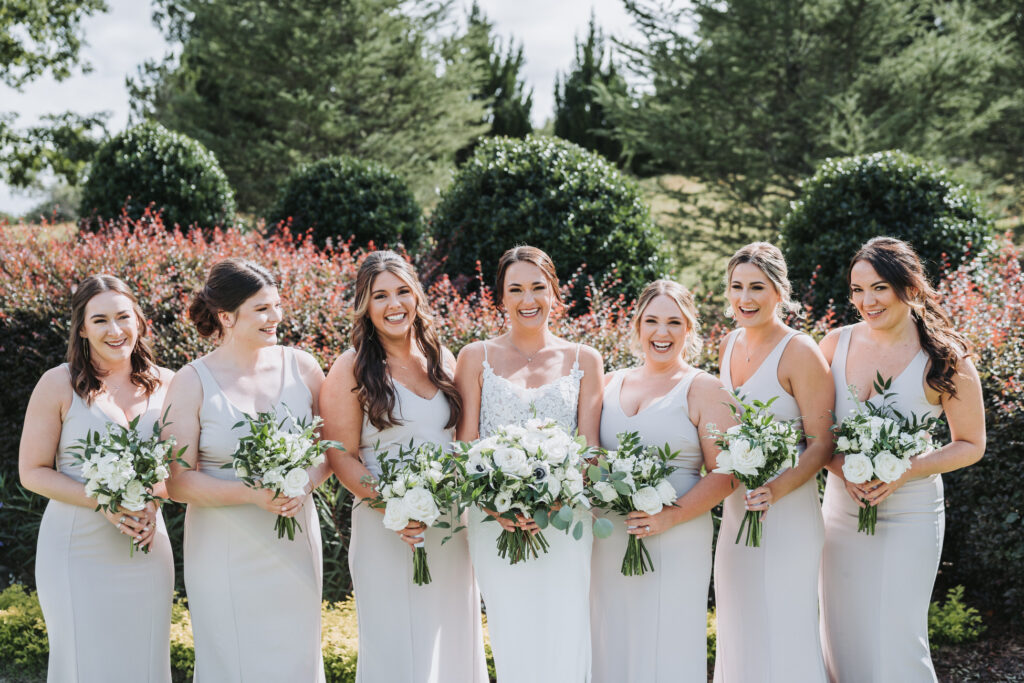 Bride and Bridesmaids smile at camera at Yonah Mountain vineyard wedding.