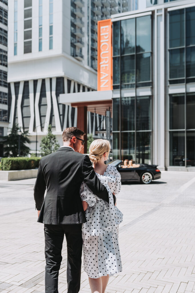 Couple walks to their sports car during their city engagement session.