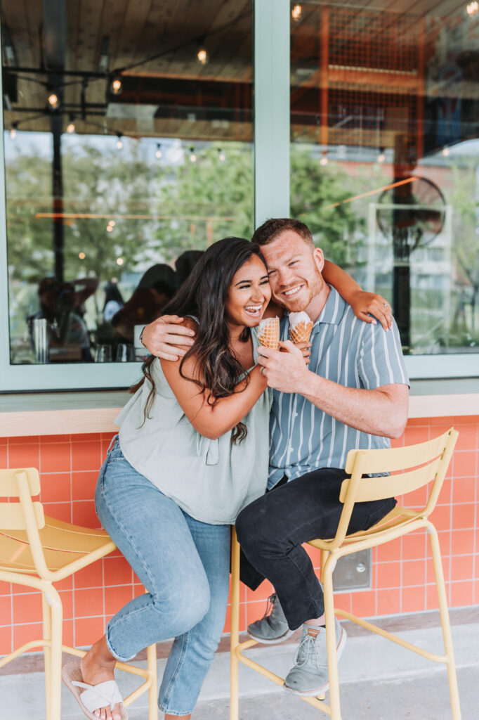 Couple laughs as they eat their ice cream.