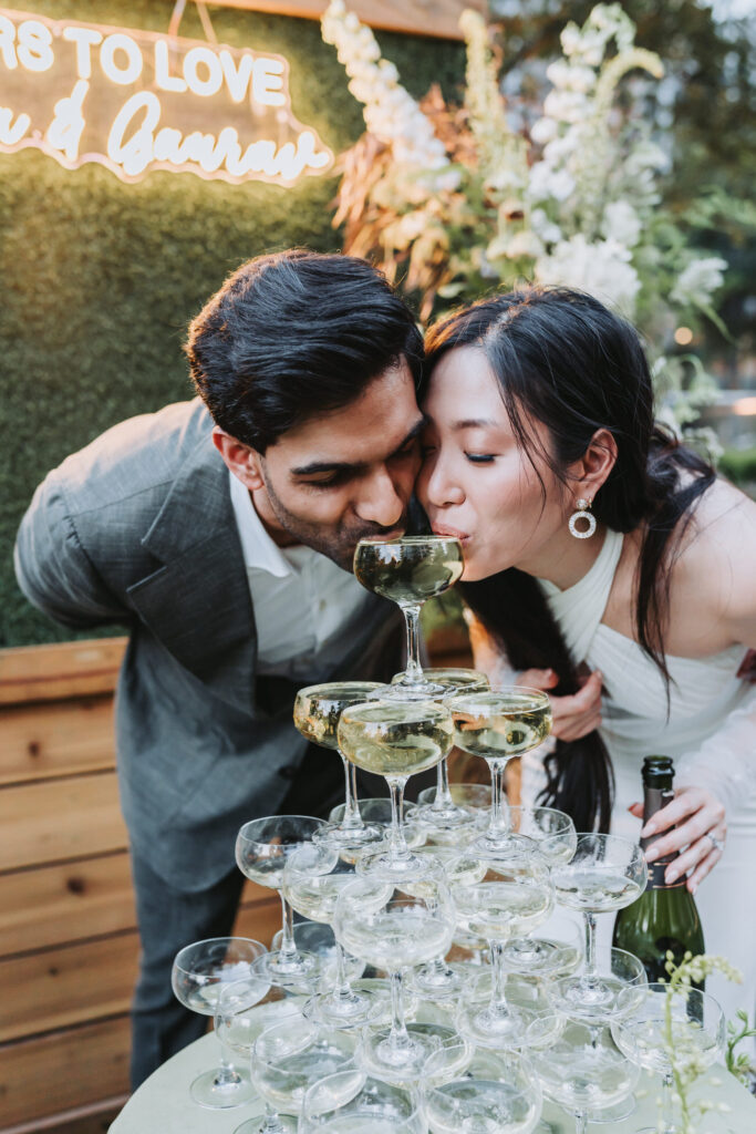 Bride and groom drink from their champagne tower