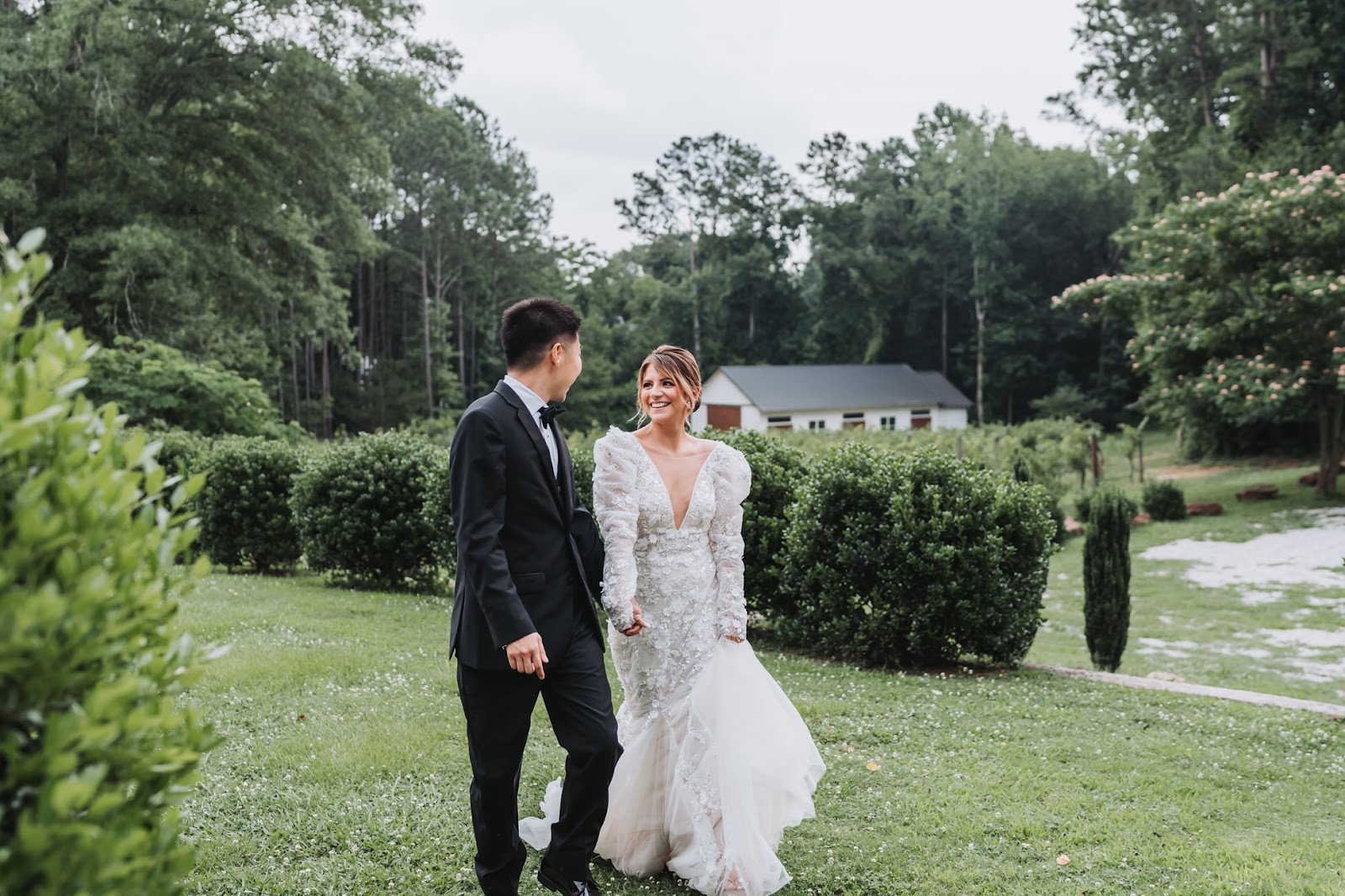 bride and groom being photographed walking on venue lawn