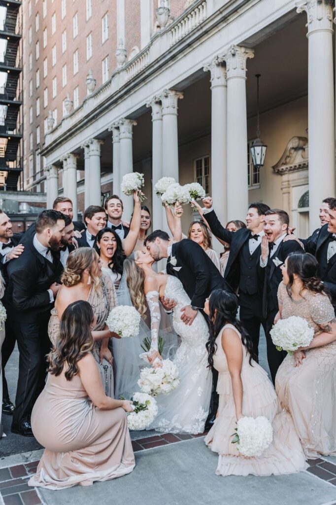 Groom kisses bride and Wedding party cheers while photographed at The Biltmore Ballrooms