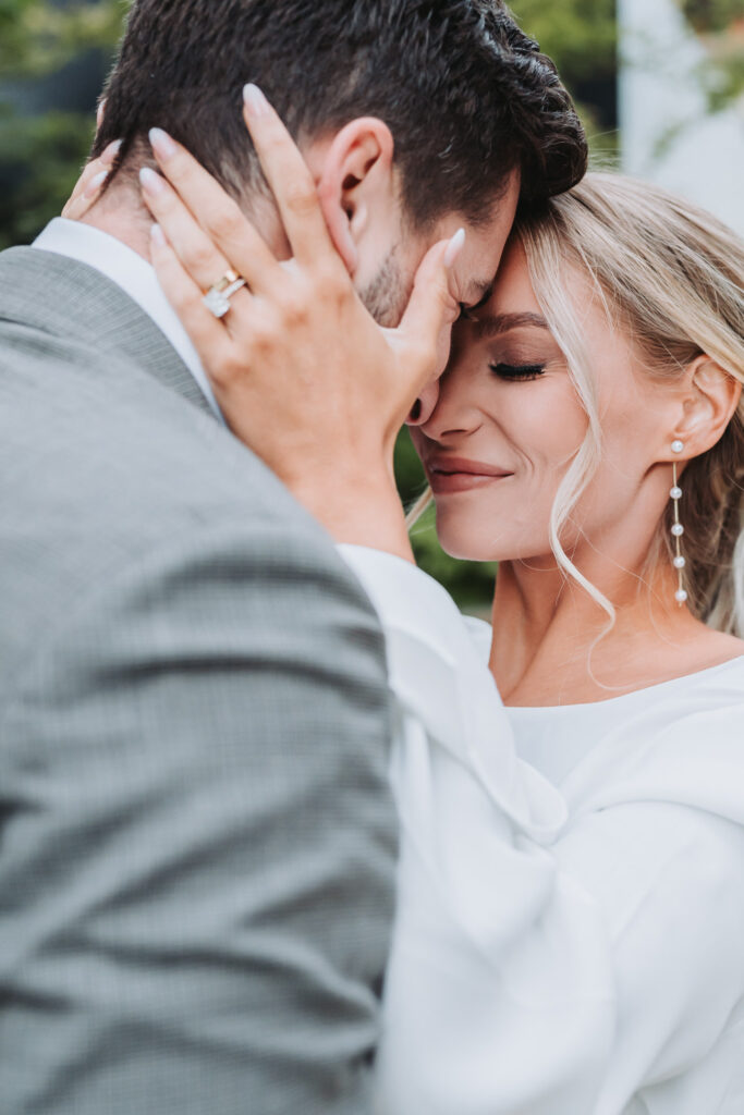 girl holds guy's face showing off engagement ring.