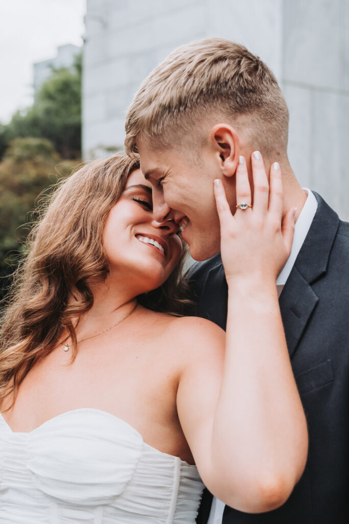 girl holds guys face and smiles.