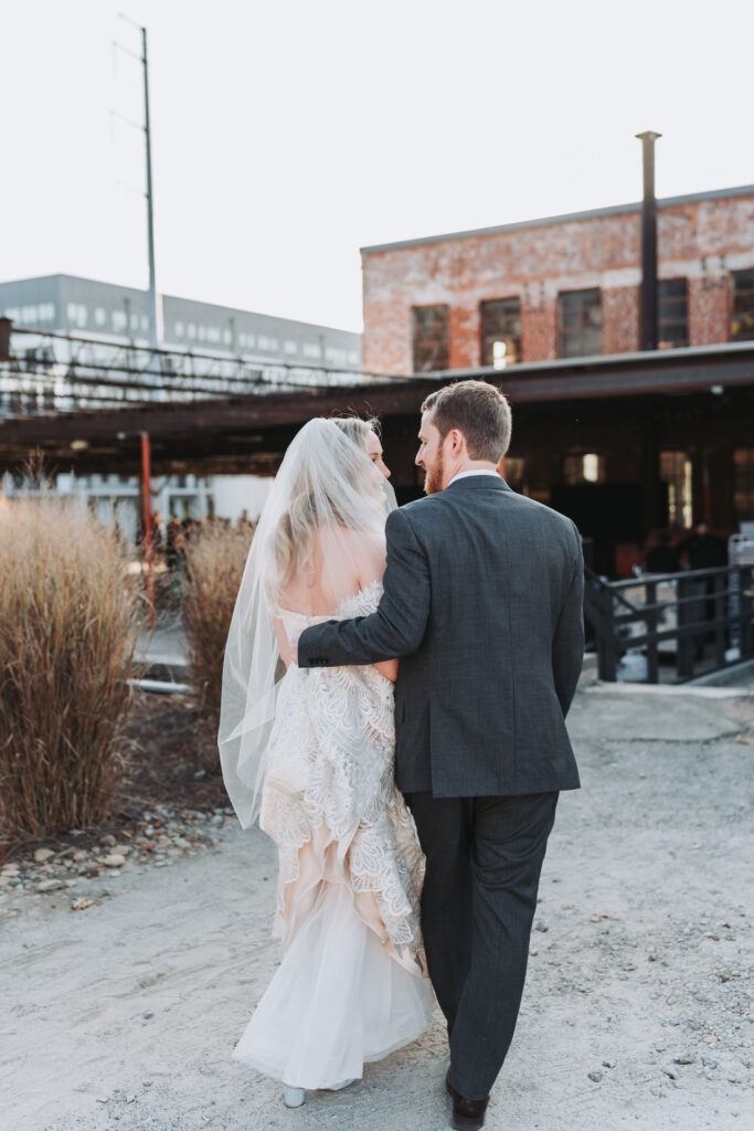 bride and groom look at each other as they walk.