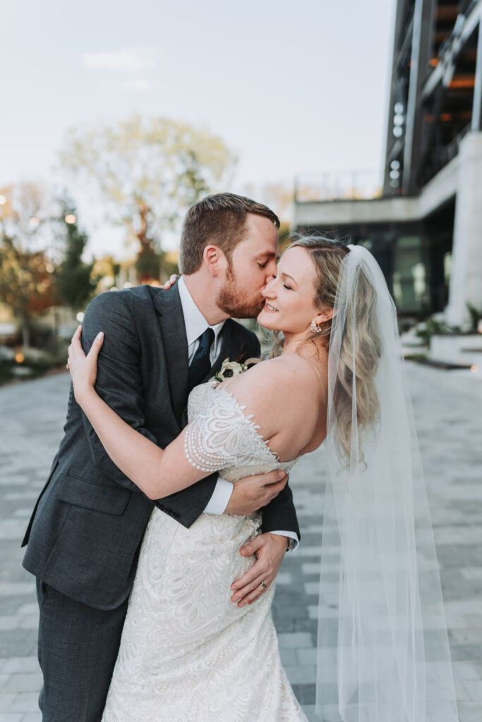 groom dips bride back and kisses her cheek.