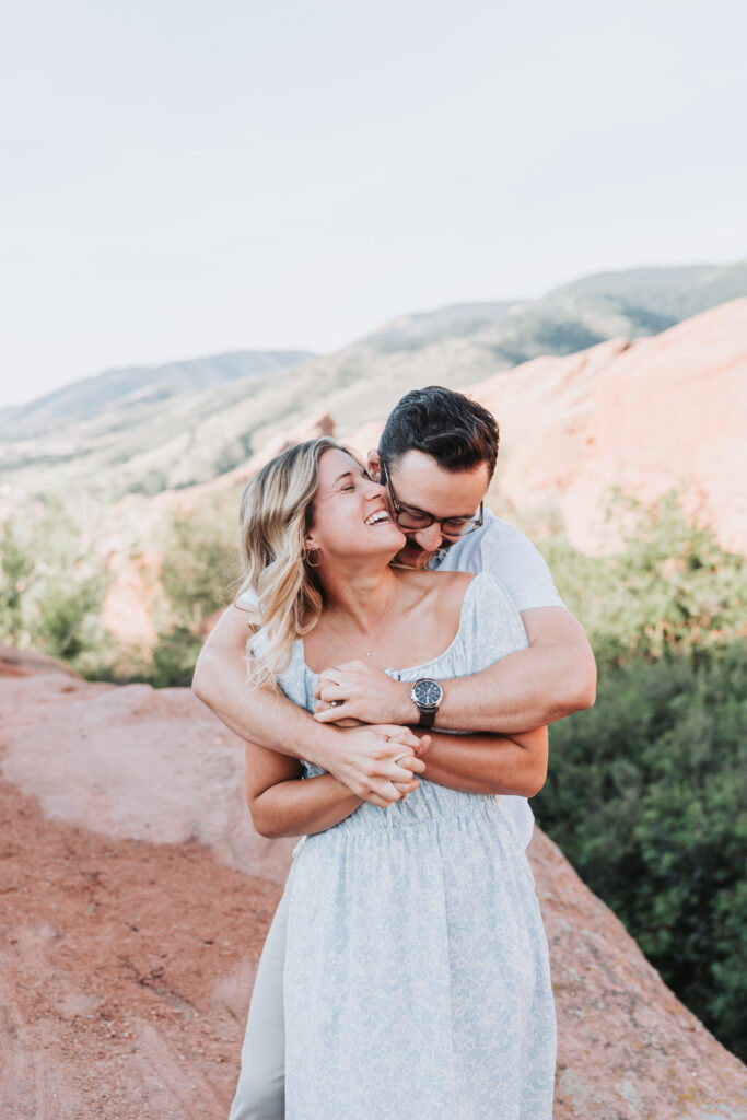 guy snuggles up to girl while mountain views in the background