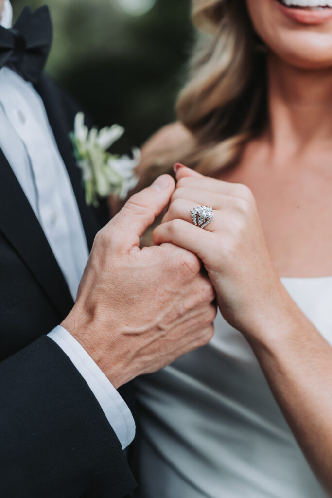 guy holds girls hand while showing off engagement ring.