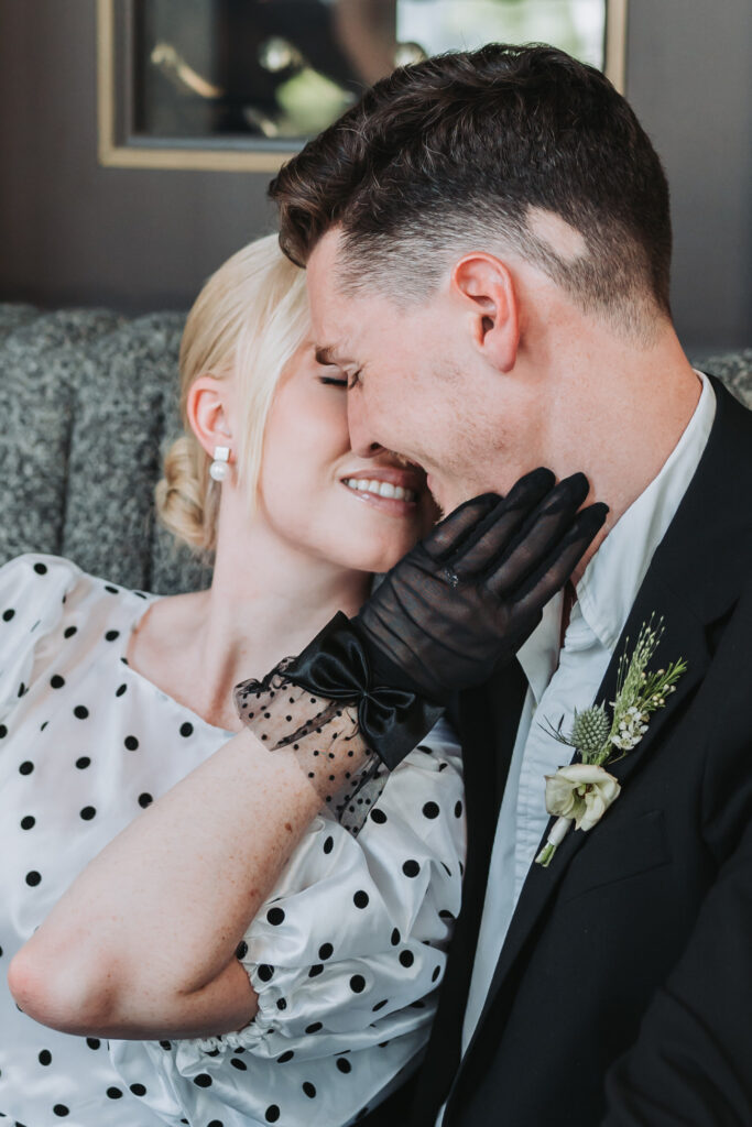girl holds guys face for a kiss while showing her engagement ring.