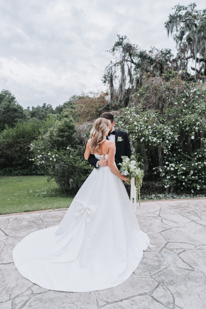 Groom holds bride close and the back of her dress shows a bow