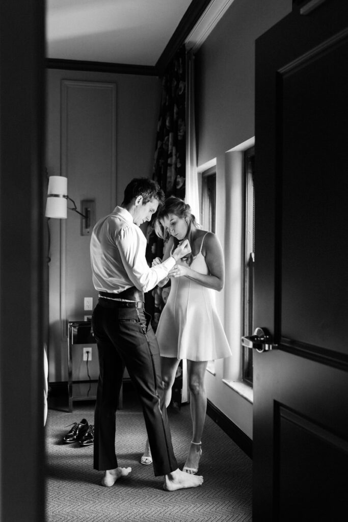 woman and man get dressed together for their engagement photos