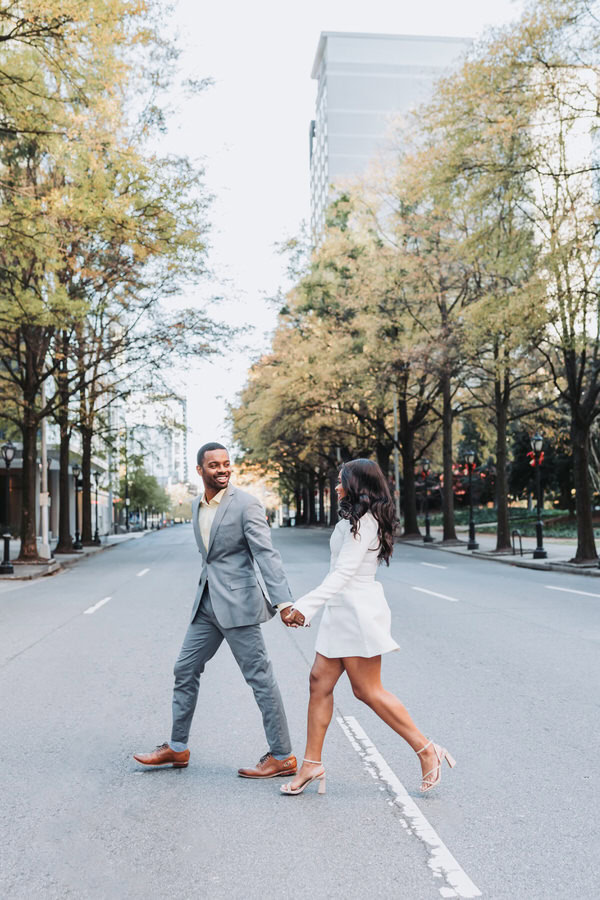 Engaged couple runs through the streets of Atlanta Midtown.