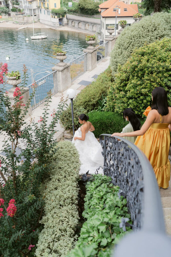 Bride and bridesmaids walk down spiral staircase overlooking lake como